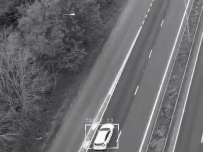 The minted LOCK tracking the same white car as it recedes up the highway.